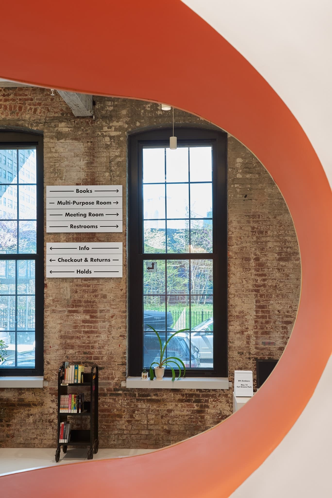 Photo of wayfinding directionals seen through an ellipse-shaped wall cutout in the kids area